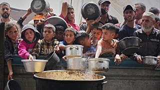 Palestinians wait to get food at a community kitchen in Khan Younis, 24 April, 2025