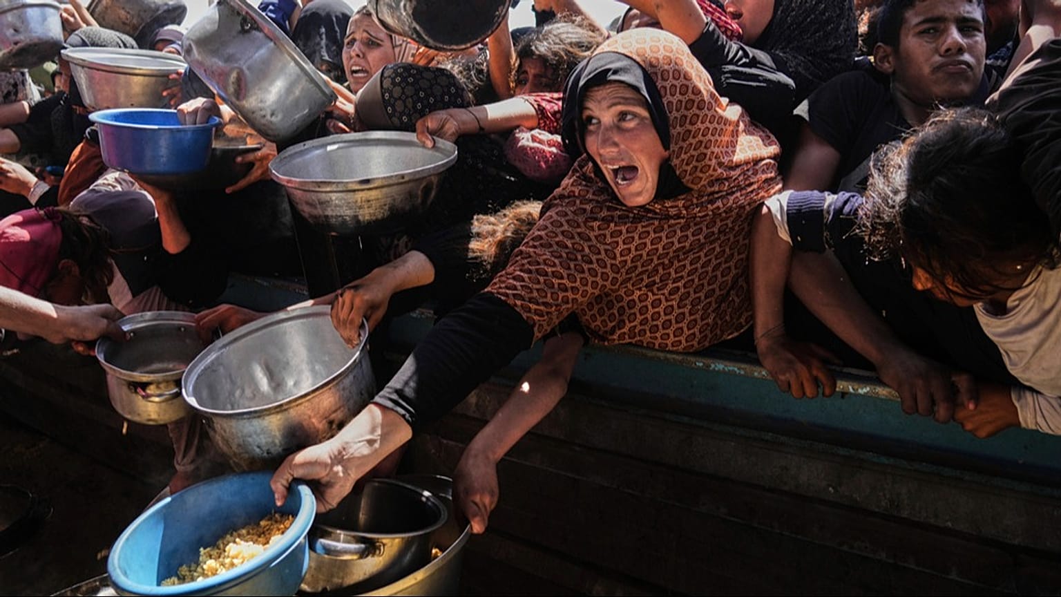 Palestinesi cercano di ricevere cibo donato in una cucina comunitaria a Khan Younis, nel sud della Striscia di Gaza, 9 maggio 2025
