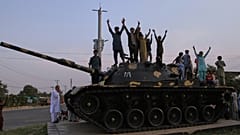 Paquistaneses fazem sinais de vitória enquanto festejam em cima de um modelo de um tanque, depois de a Índia e o Paquistão terem chegado a um acordo de cessar-fogo, em Multan