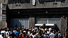 موظفو الحكومة الفلسطينية يتزاحمون لسحب الأموال من أجهزة الصراف الآلي في أحد البنوك التي أغلقت أبوابها لمدة أسبوع، في مدينة غزة يوم الأربعاء 11 يونيو 2014.  