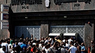 Funcionários do governo palestiniano lutam para levantar dinheiro de caixas multibanco num banco que está fechado há uma semana, na Cidade de Gaza, na quarta-feira, 11 de junho de 2014.