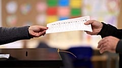 Um homem segura uma lista de candidatos antes de votar numa assembleia de voto em Espinho, no norte de Portugal, no domingo, 10 de março de 2024