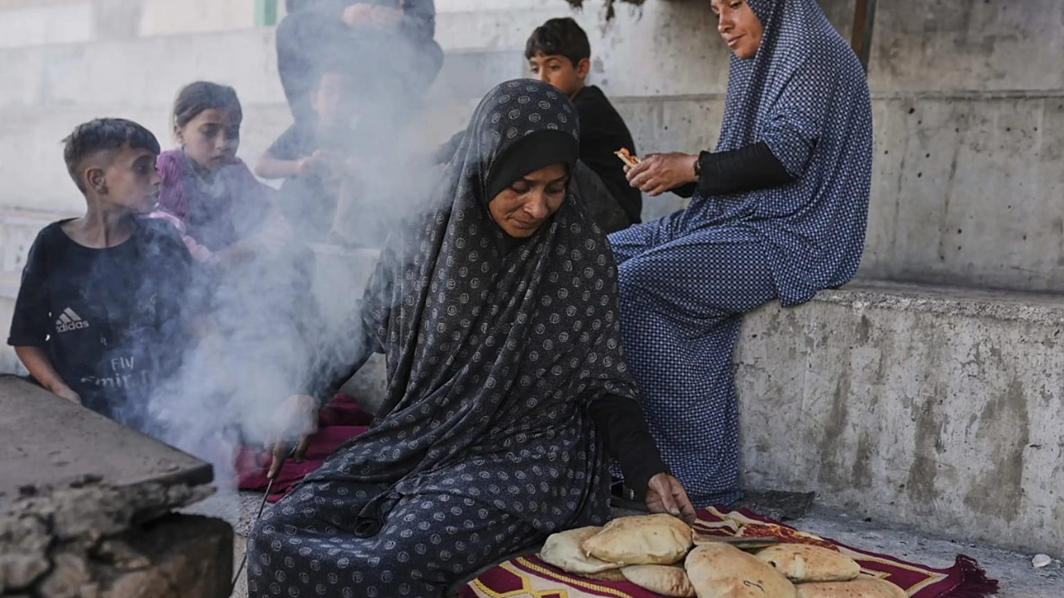 فلس��ينية في غزة تخبز رغيف الخبز لأطفالها
