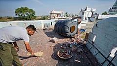 Um aldeão limpa o telhado da sua casa danificada por um bombardeamento de artilharia paquistanesa em RS Pura, ao longo da fronteira internacional, Índia, 12 de maio de 2025.