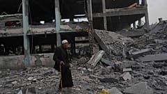 Un anciano palestino camina frente a un edificio destruido por los bombardeos israelíes.