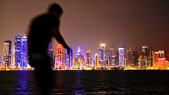 Sur cette photo du vendredi 2 novembre 2018, un homme marche avec pour toile de fond la ligne d'horizon de Doha, au Qatar.