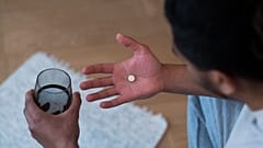 Um homem prepara-se para tomar um comprimido.