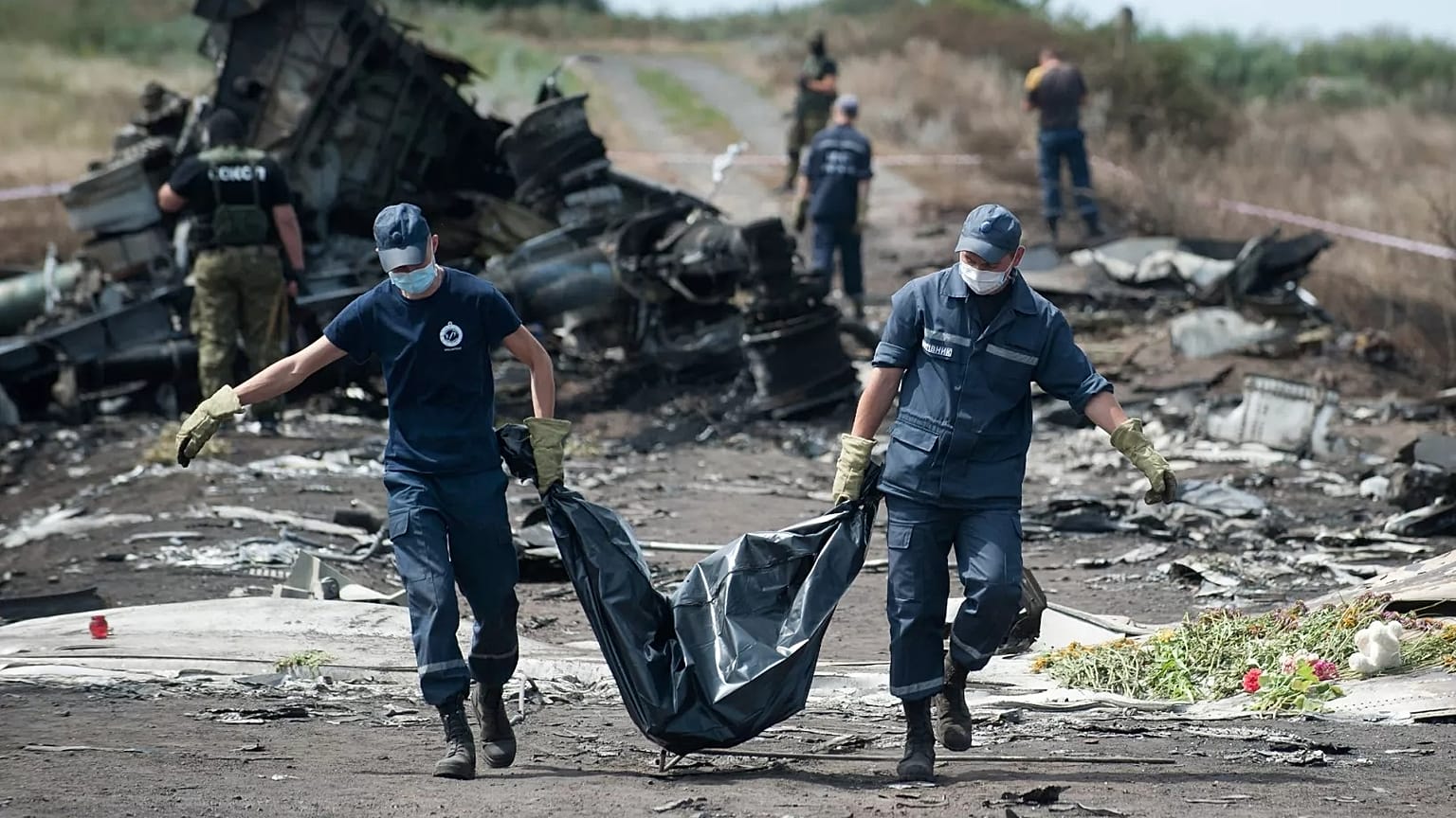  Rus yanlısı savaşçılar Malezya Havayolları'na ait MH17 sefer sayılı uçağın düştüğü yerde nöbet tutarken Ukraynalı Acil Yardım çalışanları bir kurbanın cesedini ceset torbasında taşıyor, 20 Temmuz 2014.