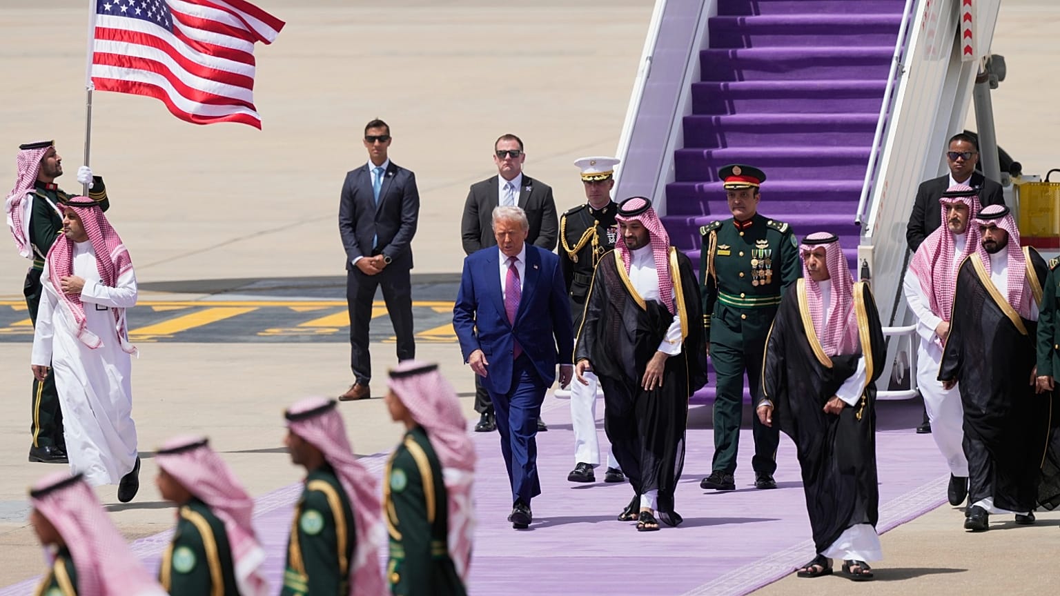 الرئيس دونالد ترامب يسير إلى جانب ولي العهد السعودي الأمير محمد بن سلمان بعد وصوله إلى مطار الملك خالد الدولي في الرياض الثلاثاء 13 مايو 2025.