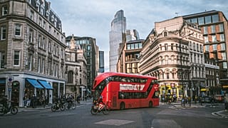 A double-decker red bus on a road in central London, United Kingdom.