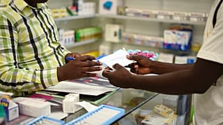 FILE — A man buys a face mask at a pharmacy in Kitwe, Zambia, Feb. 6, 2020