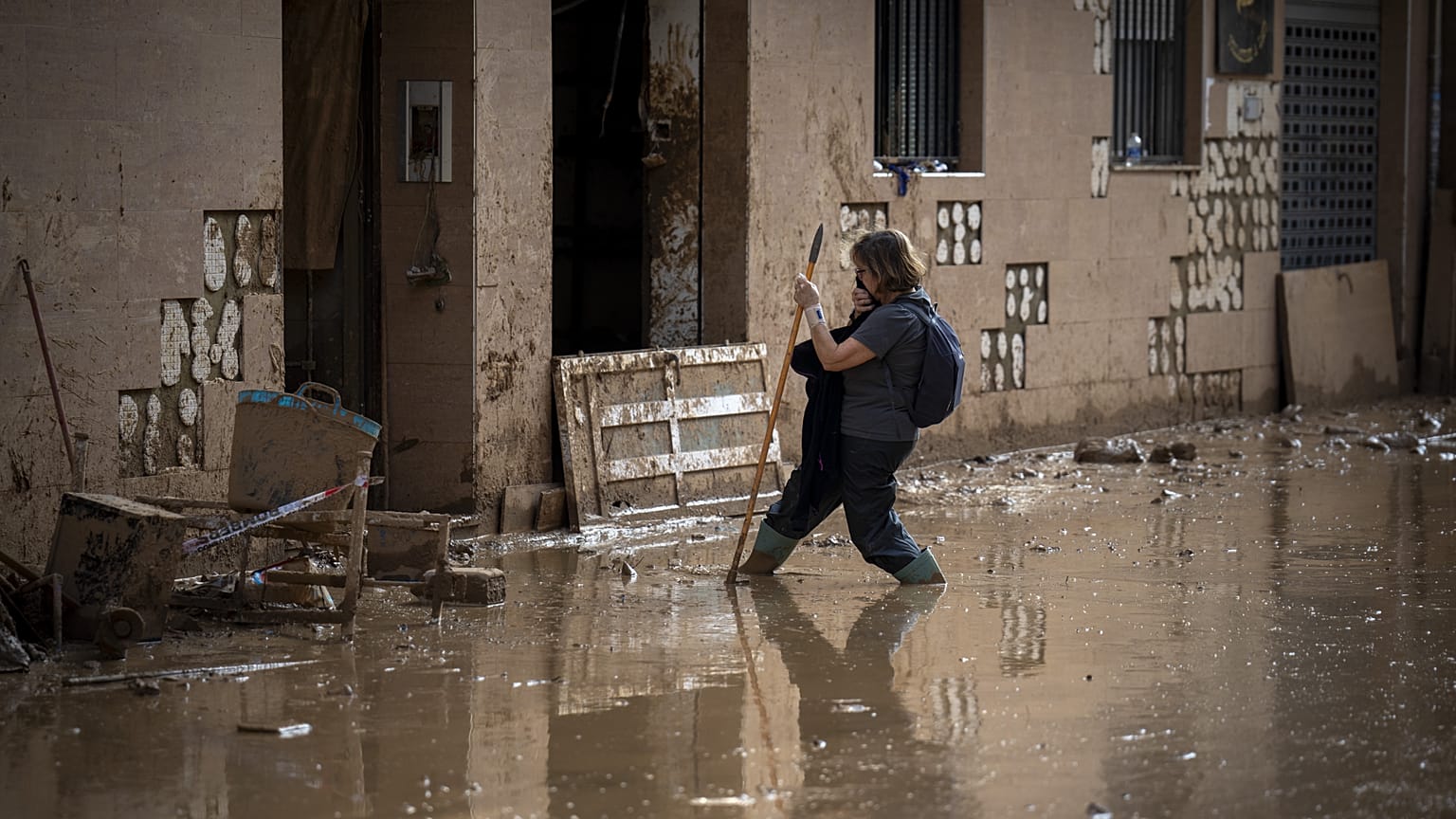A woman walks through the mud as she tries to arrive at her home on a still flooded street in Valencia, 7 November, 2024