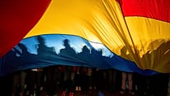 Pessoas projectam sombras sobre uma bandeira romena durante um comício eleitoral do candidato presidencial Nicusor Dan, uma semana antes da segunda volta das eleições presidenciais do país