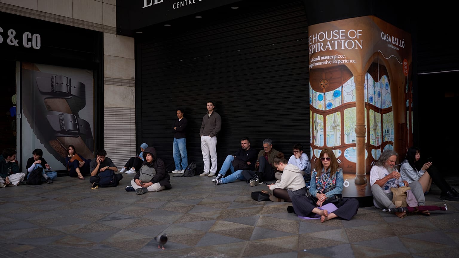 People wait outside a closed shopping center, during a blackout in Barcelona, 28 April 2025