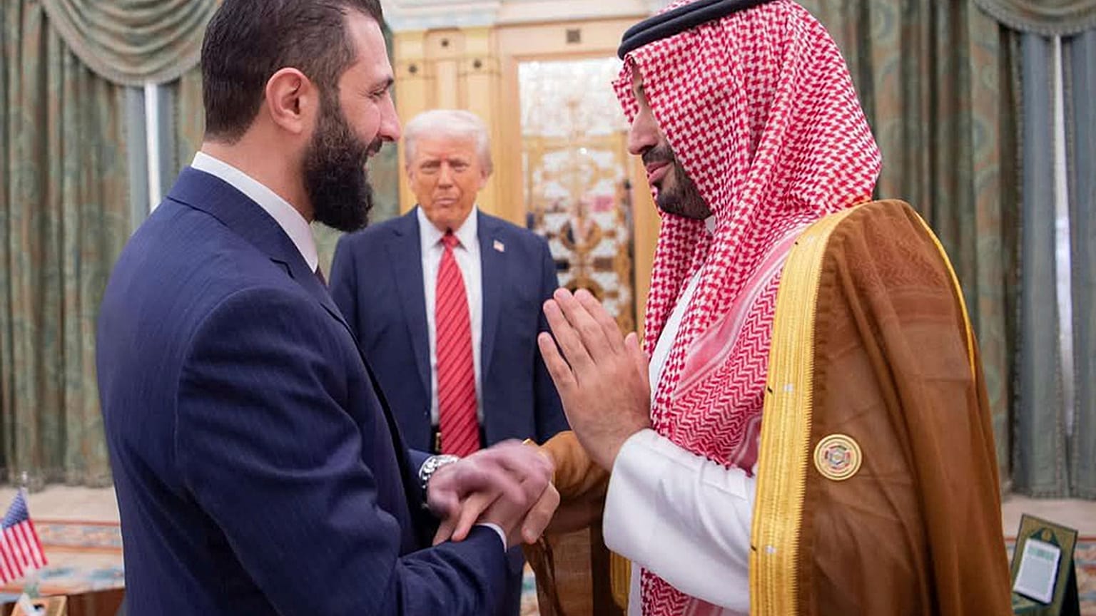  الرئيس دونالد ترامب ، في الوسط ، ينظر إلى ولي العهد السعودي الأمير محمد بن سلمان ، على اليمين ، يصافح الرئيس السوري المؤقت أحمد الشرع ، في الرياض ، المملكة العربية السعودية ،