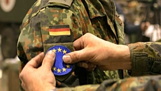 Symbolbild: Ein deutscher Soldaten erhaelt am 30. November 2004 in Sarajevo eine EU-Flagge auf die Schulter, als das Mandat zur EUFOR geaendert wird.