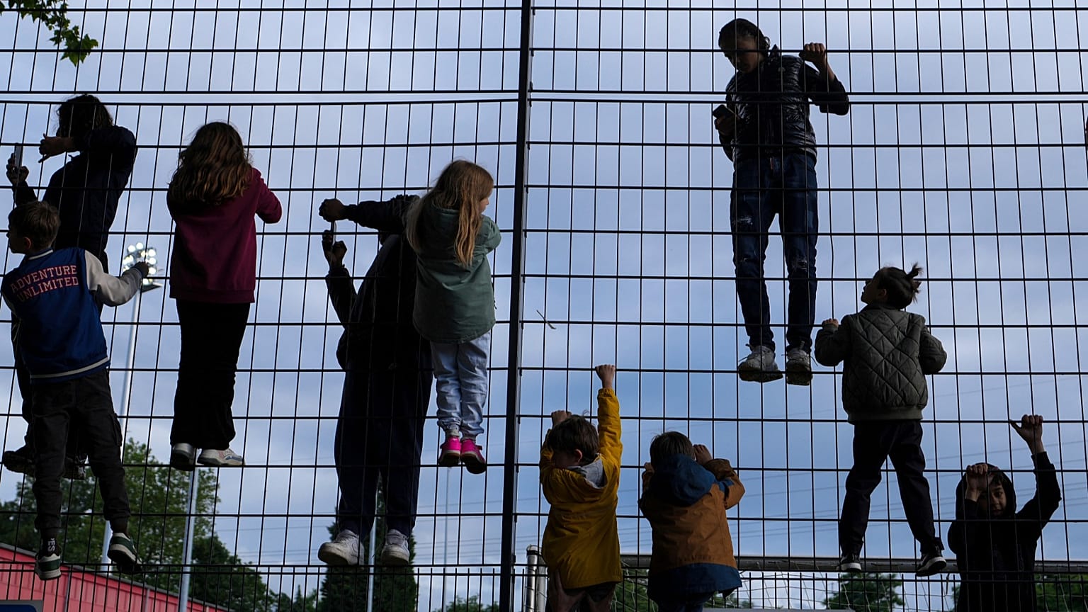 Kinder klettern an einem Zaun um einen Fußballplatz. Je nach Wohnort und Wohlstand steht ihnen eine unterschiedliche Zukunft bevor.