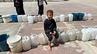 طفل ينتظر تعبئة المياه في دير البلح بقطاع غزة بتاريخ 14 مايو أيار 2025