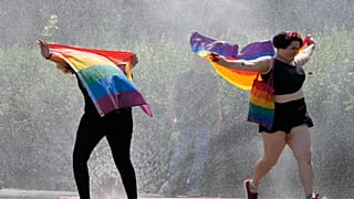 (ARCHIVO) Dos personas corriendo con la bandera LGTB