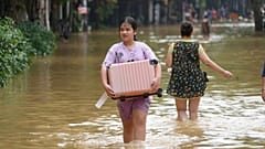 Pessoas carregando pertences caminham numa rua inundada na sequência do tufão Yagi, em Hanói, Vietname, a 12 de setembro de 2024. 