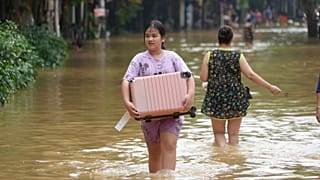 People carrying belongings wade in flooded street in the aftermath of Typhoon Yagi, in Hanoi, Vietnam on 12 September 2024.