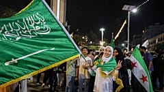 فتاة تحمل العلم السعودي في حمص ، سوريا ، الثلاثاء 13 مايو 2025 ، وهي تحتفل بخطة الرئيس الأمريكي دونالد ترامب لتخفيف العقوبات على سوريا وتطبيع العلاقات مع حكومتها الجديدة.