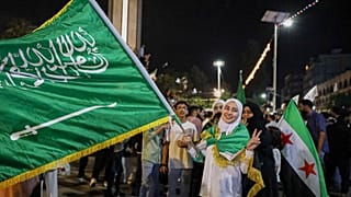فتاة تحمل العلم السعودي في حمص ، سوريا ، الثلاثاء 13 مايو 2025 ، وهي تحتفل بخطة الرئيس الأمريكي دونالد ترامب لتخفيف العقوبات على سوريا وتطبيع العلاقات مع حكومتها الجديدة.