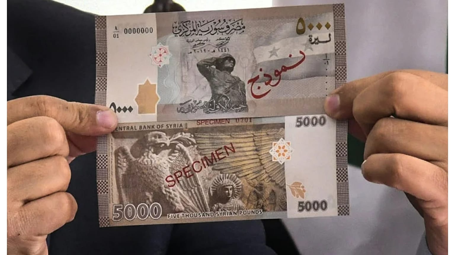 الصورة تعود إلى 24 يناير 2021 ويظهر فيها إياد بلال، مدير مديرية الخزينة يومها في مصرف سوريا المركزي، وهو يحمل الورقة النقدية من فئة 5000 ليرة سورية خلال مؤتمر صحفي بدمشق.