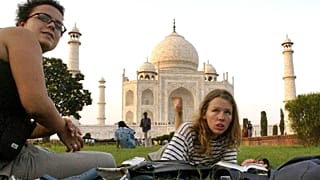 Turistler Hindistan'ın Agra kentindeki Tac Mahal'in çimlerinde oturuyor.