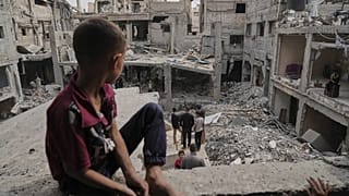 طفل فلسطيني يجلس على ركام منزله في غزة