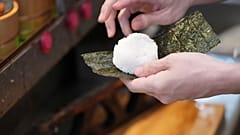 Yosuke Miura, Tokyo'nun en eski onigiri restoranı olan Onigiri Asakusa Yadoroku'da bir pirinç topunun etrafına deniz yosunu sarıyor, 3 Haziran 2025.