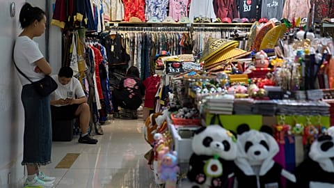 Vendors wait for customers at their store selling clothing and souvenirs inside a mall in Beijing on May 15, 2025. 