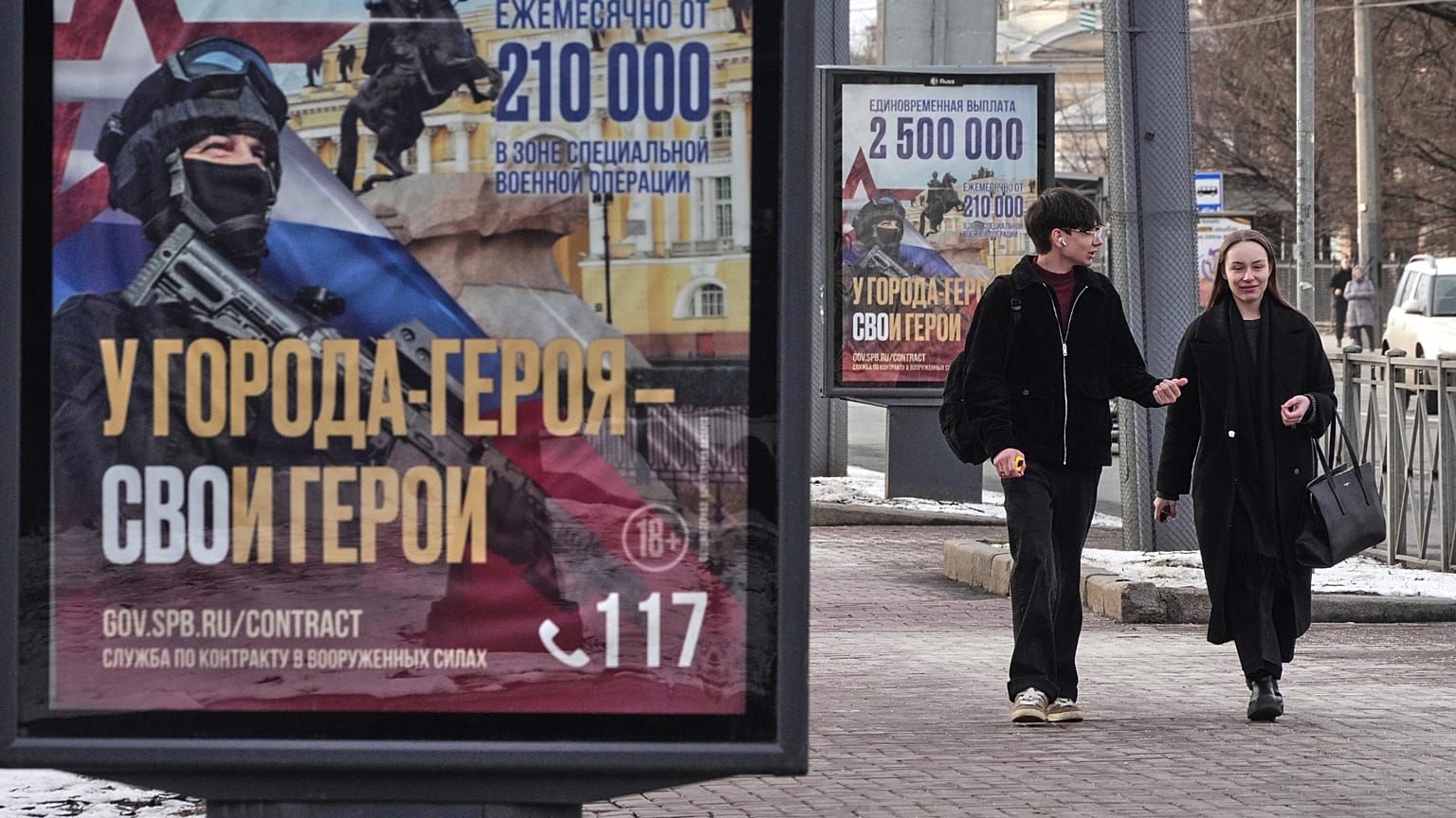 FILE: A couple walk past billboards calling for a contract for service in the Russian armed forces in St Petersburg, 15 March 2025