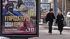FILE: A couple walk past billboards calling for a contract for service in the Russian armed forces in St Petersburg, 15 March 2025