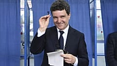 Le candidat à la présidence Nicusor Dan sourit en tenant un timbre avant de déposer son bulletin de vote lors du second tour de l'élection présidentielle à Fagaras, en Roumanie, 