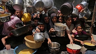 Palestinianos lutam para obter alimentos doados numa cozinha comunitária em Jabalia, 19 de maio de 2025