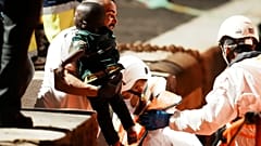طفل صغير، بين ذراعي أحد عمال الإنقاذ البحري
