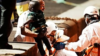 Un bambino piccolo, tra le braccia di un operatore del Salvamento Marítimo