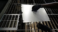 Un trabajador levanta una chapa de acero tras cortarla con un diseño específico en una fábrica de un suburbio de Bengaluru (India).