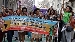 Activistas marchan con una pancarta que reza en portugués "Mujeres negras contra el racismo, el genocidio y el feminicidio. Nuestras vidas importan", durante una manifestación