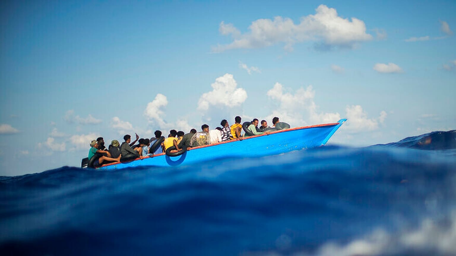 FILE - Migranci płyną drewnianą łodzią na południe od włoskiej wyspy Lampedusa na Morzu Śródziemnym, 11 sierpnia 2022 r.
