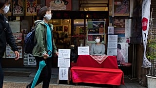 Buchiko adlı bir falcı, Tokyo'daki bir alışveriş caddesinde yürüyenlere bakıyor, 15 Ekim 2020.