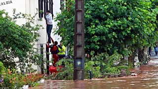 Un equipo de rescate ayuda a un hombre a salir de su casa en Cambo-Les-Bains, suroeste de Francia, viernes 4 de julio de 2014.