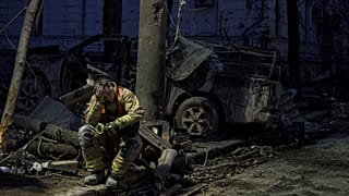 A rescue worker rests near university building destroyed by a Russian missile strike on Sumy, 13 April, 2025