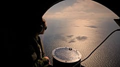 Um membro da tripulação de um avião da Marinha francesa observa o mar durante um exercício militar da NATO e uma missão de deteção de minas marítimas sobre o Mar Negro, 9 de abril de 2025