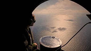 Um membro da tripulação de um avião da Marinha francesa observa o mar durante um exercício militar da NATO e uma missão de deteção de minas marítimas sobre o Mar Negro, 9 de abril de 2025