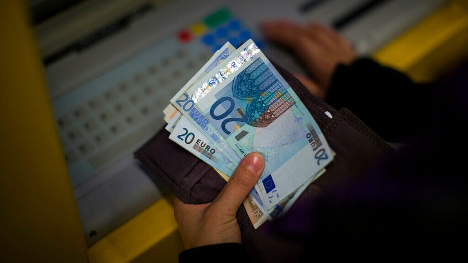 FILE: A woman holds euros bills after withdrawing her money from a cash machine in Barcelona, Spain, Wednesday Jan. 23, 2013.