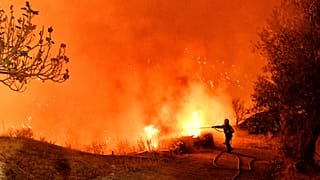 Um bombeiro tenta extinguir as chamas perto da aldeia de Kallithea, 29 de setembro de 2024