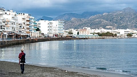 FILE- A woman walks on the beach of Ierapetra on the southeast coast of the Greek island of Crete on Thursday, Nov. 25, 2014.