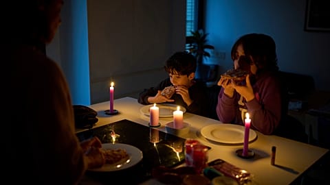 A family eats a snack by candlelight during a blackout in Barcelona, Spain, Monday, April 28, 2025. 